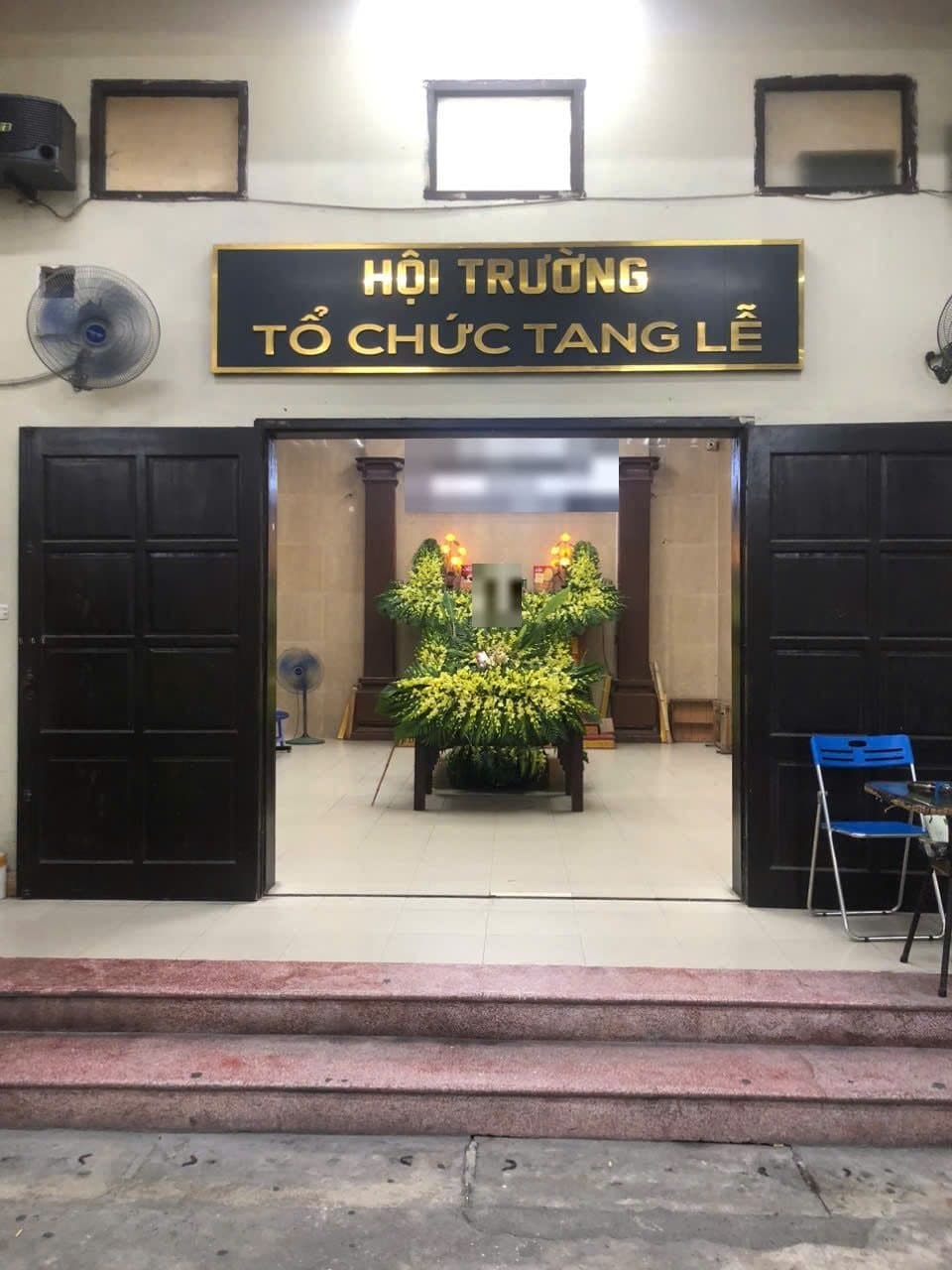 Mặt tiền hội trường tổ chức tang lễ, cửa mở nhìn thẳng vào hương án hoa vàng