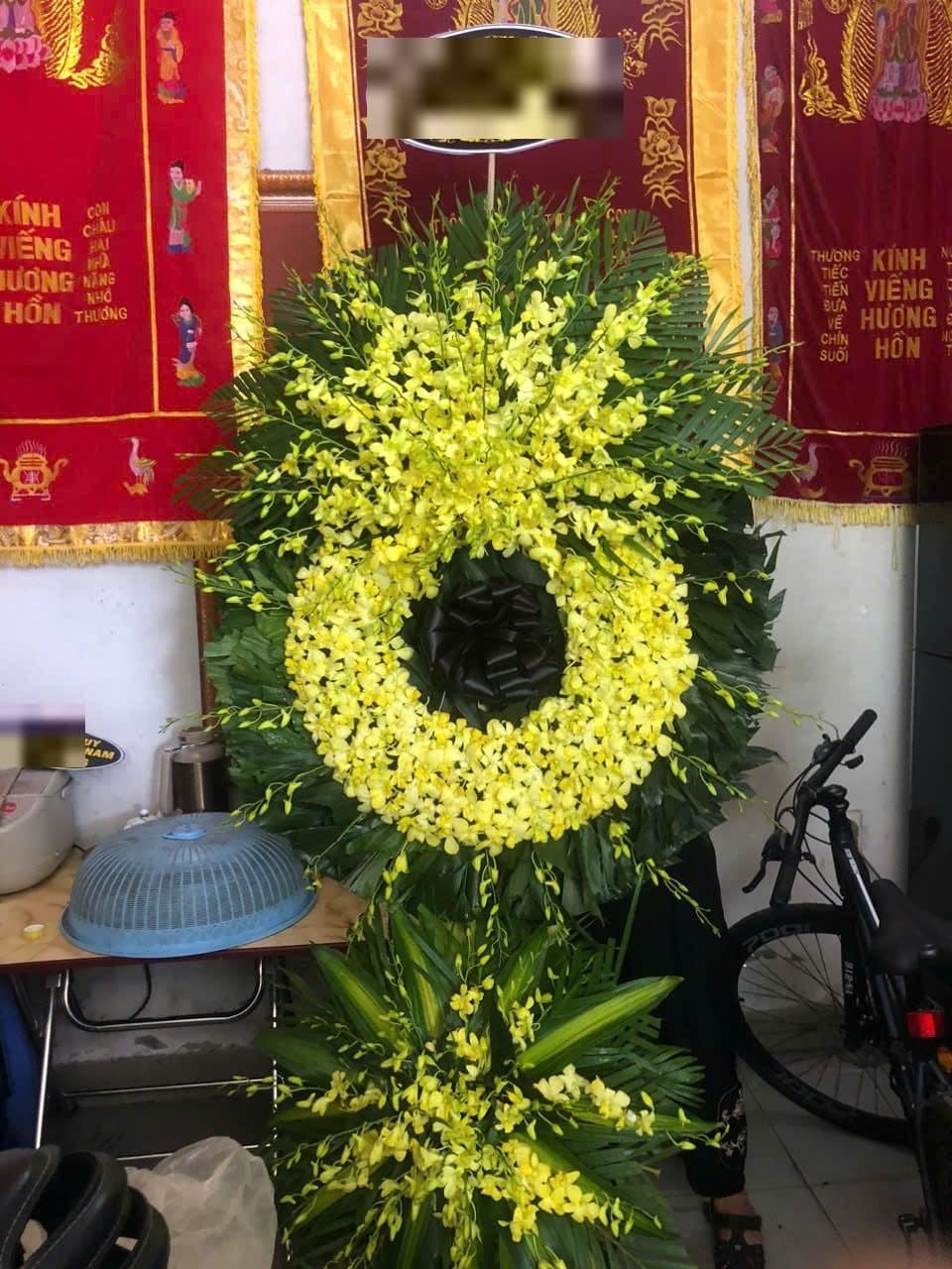 Vòng hoa viếng kết lan vàng viền lá, tâm thắt nơ đen